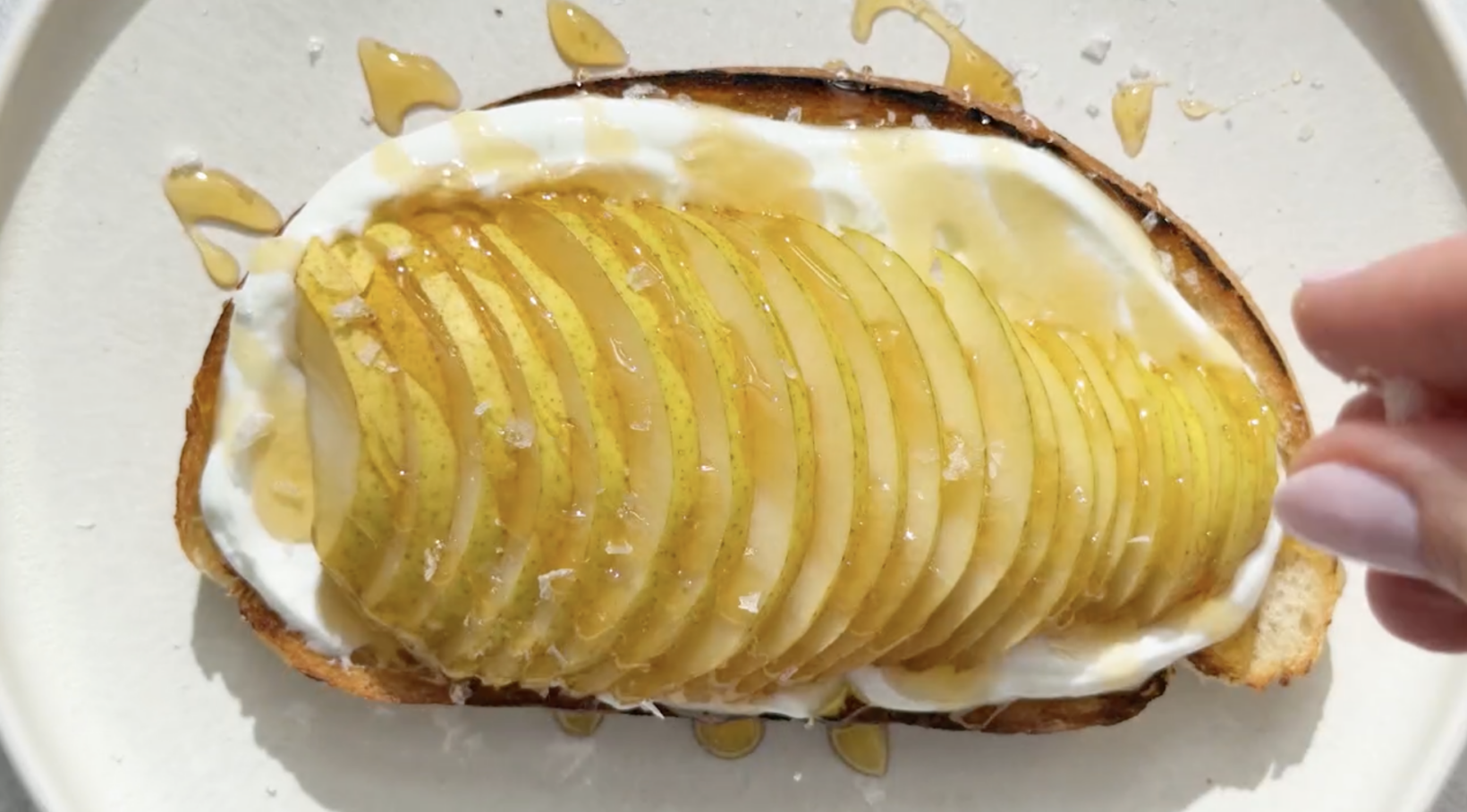 Breakfast toast topped with yogurt, thinly sliced pear, Nate's organic honey, and sea salt.